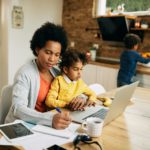 African American single mother with two kids working at home.